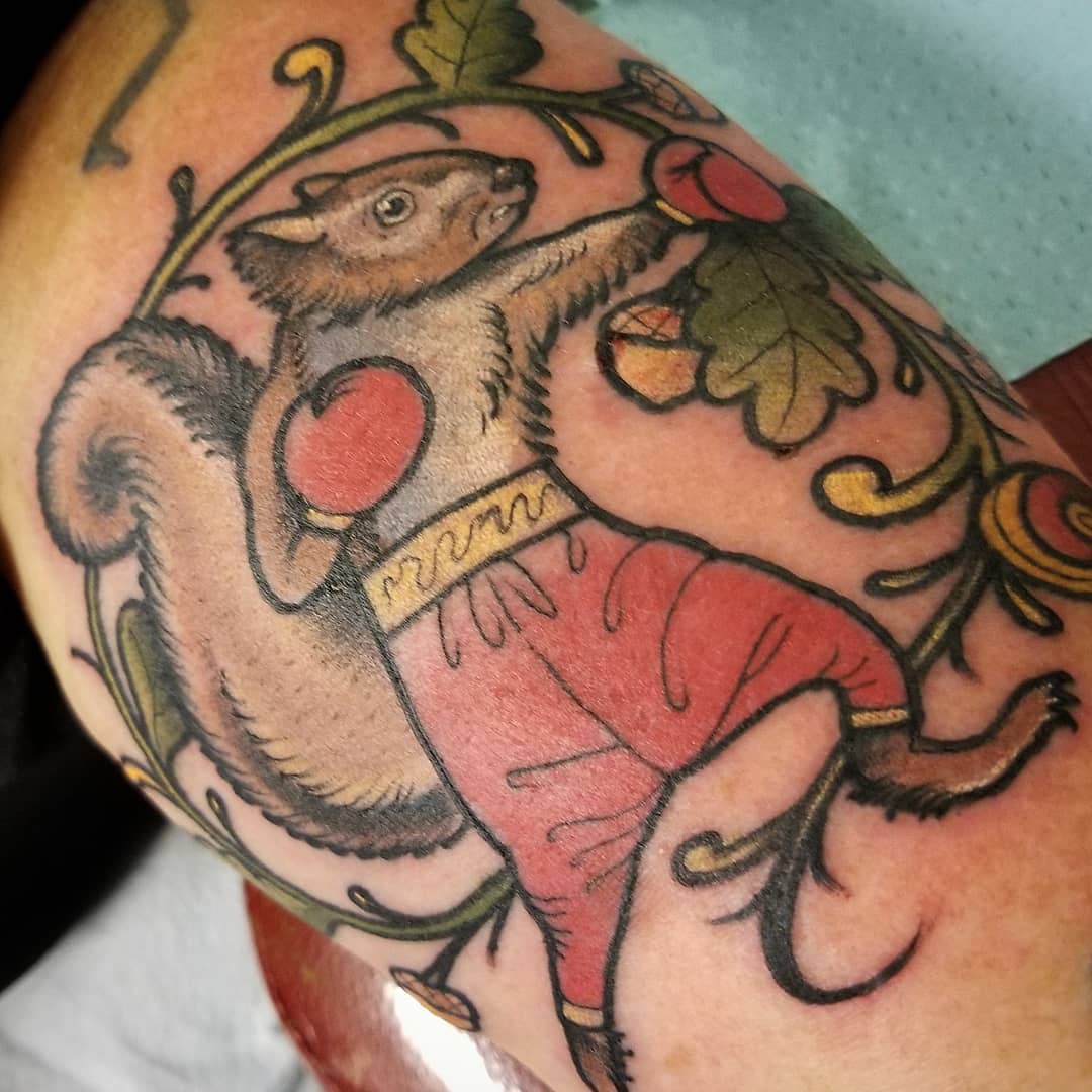 Tattoo of a boxing squirrel wearing red shorts with acorns and leaves in the background